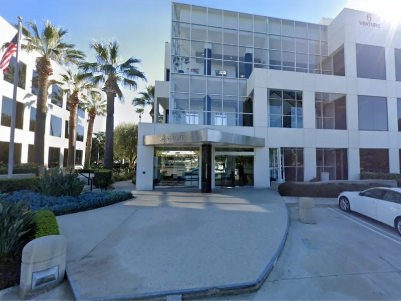Modern three-story HRX CPAs office building with glass windows and palm trees in Irvine, California